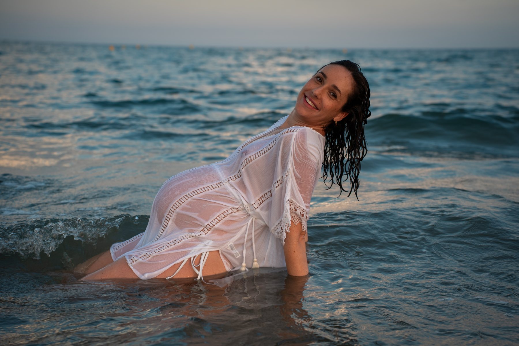 Future maman dans les vagues au crépuscule